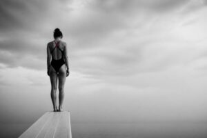 Donna sul trampolino che esita prima del tuffo: la paura di sbagliare