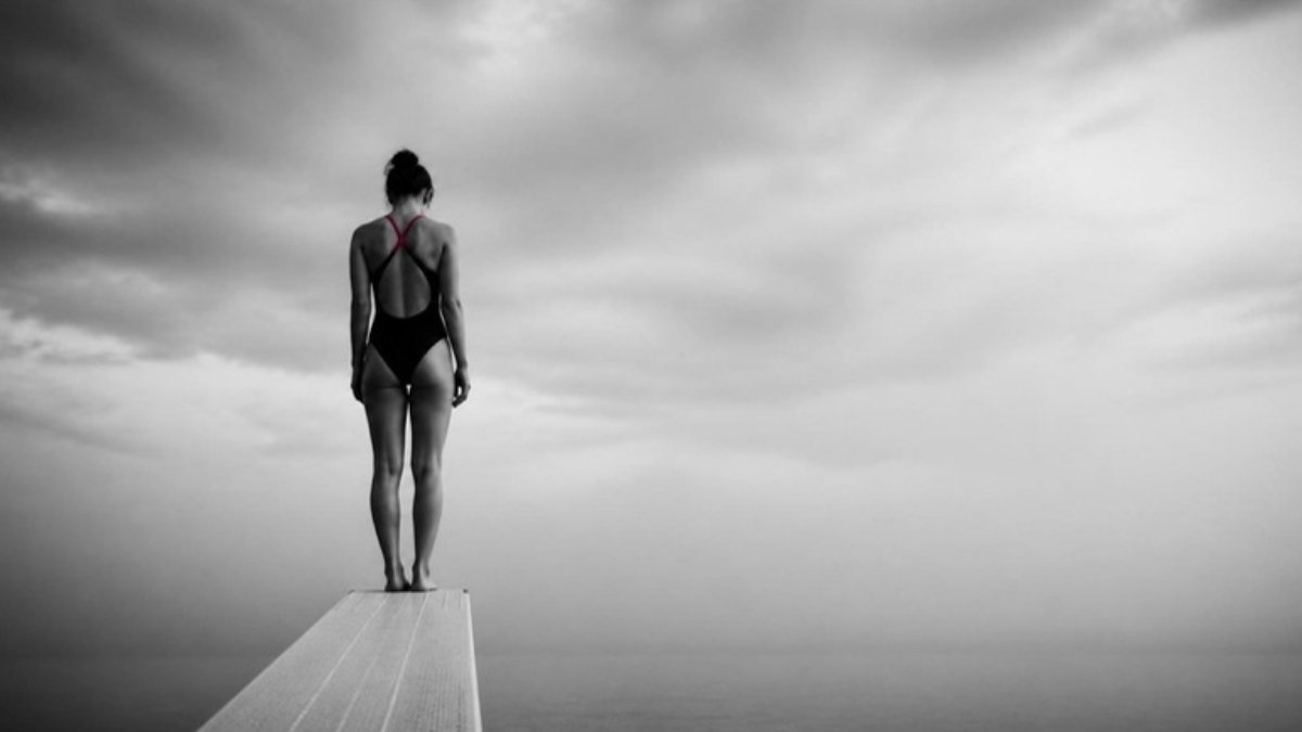 Donna sul trampolino che esita prima del tuffo: la paura di sbagliare